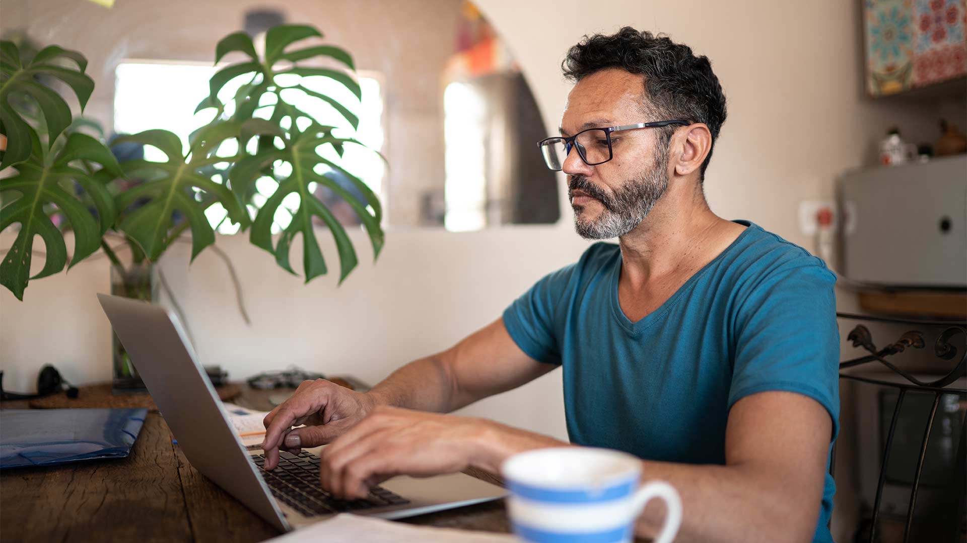 Middle-aged man sits at his dining room table applying for a HELOC on his laptop