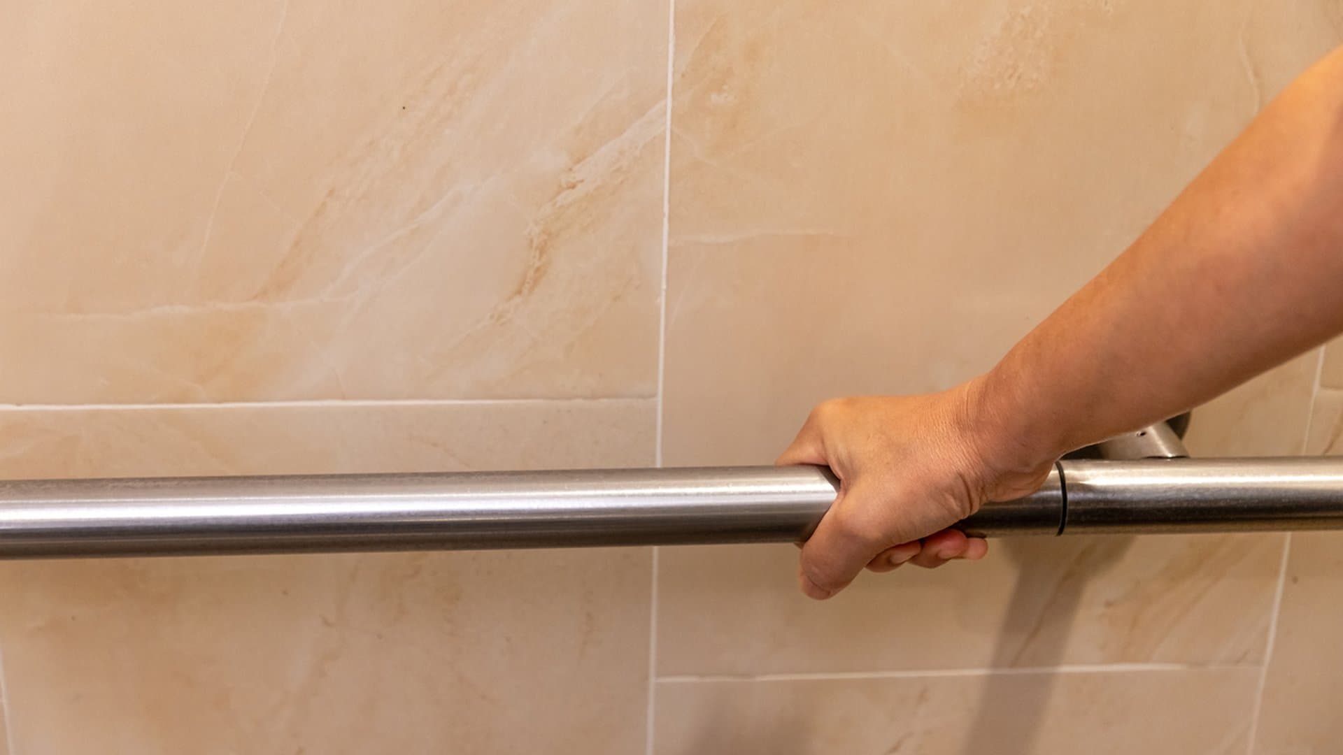 Senior holding a bathroom grab bar, an aging-in-place home safety modification